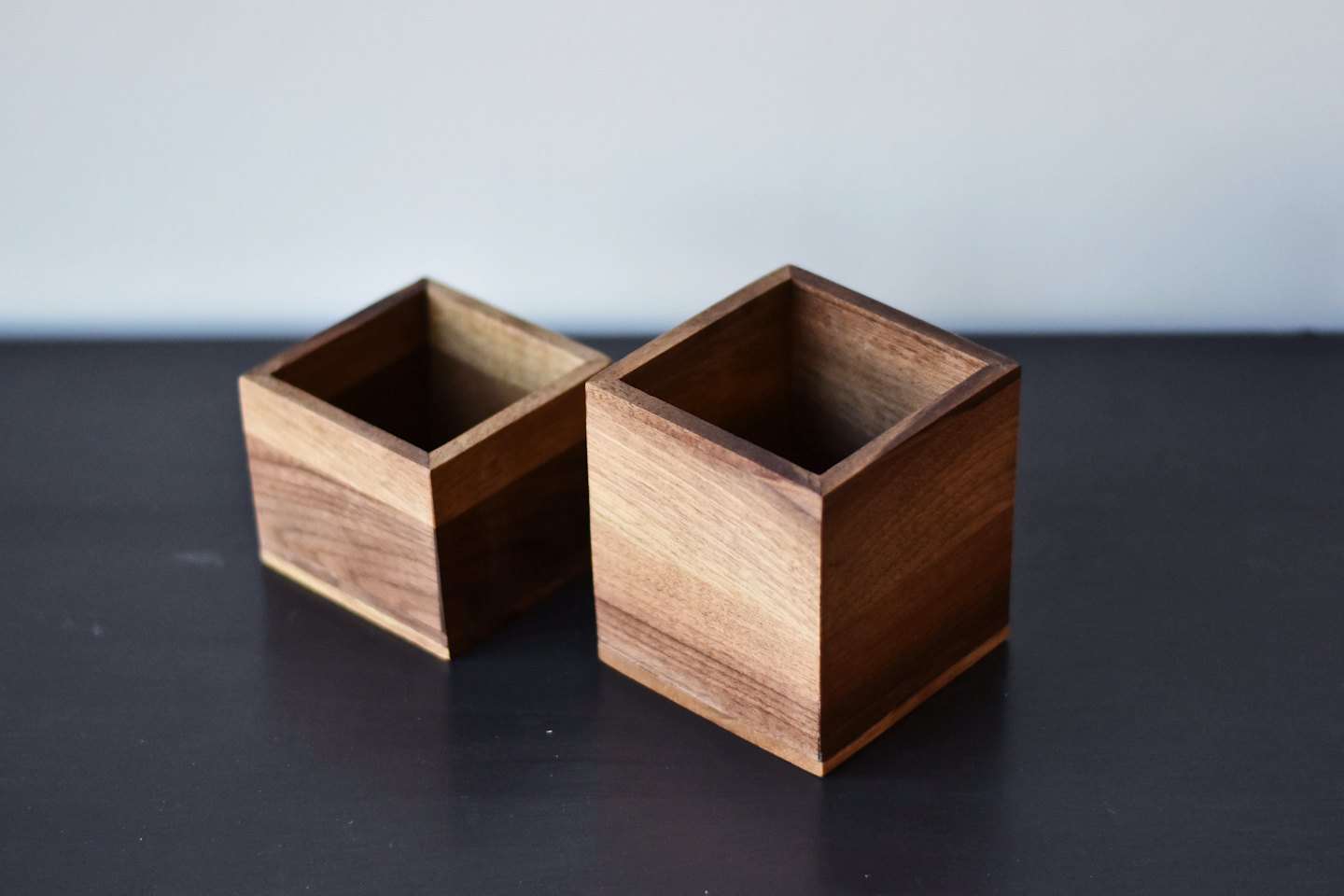 Due scatole quadrate di legno vuote su una superficie grigia.